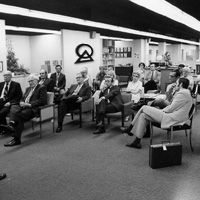 A board room with men sitting down, the RCE logo is on the wall.